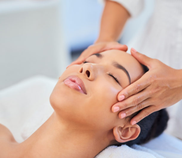 Woman gets face or facial massage at spa from beauty therapist at beauty salon for skin health and wellness treatment.